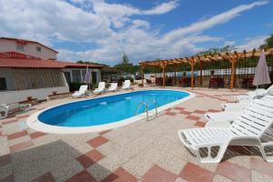 a swimming pool with lounge chairs and a patio at Pansion Comfort Sidro in Novalja