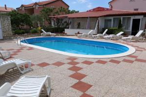a swimming pool with lounge chairs and a house at Pansion Comfort Sidro in Novalja