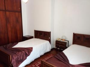 two beds in a room with white walls and wooden furniture at Pensão São Jorge in Caldas de São Jorge