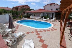 a swimming pool with lounge chairs and a house at Pansion Comfort Sidro in Novalja