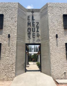 un edificio de piedra con una puerta con un cartel. en Hospedaje El Mezquite en Tequisquiapan