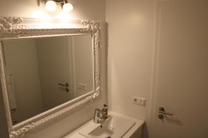 ein weißes Badezimmer mit einem Spiegel und einem Waschbecken in der Unterkunft Laxhús in Húsavík