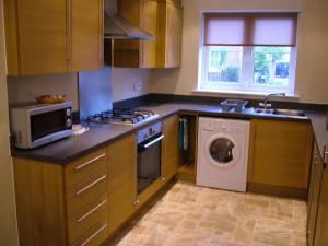 a kitchen with a washing machine and a microwave at Thistle Cottage in Mildenhall