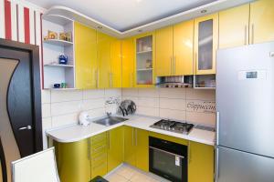 eine Küche mit gelben Schränken, einer Spüle und einem Kühlschrank in der Unterkunft VIP Apartment on Ilinska in Sumy
