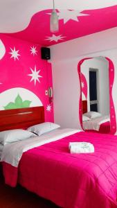 Dormitorio rosa con cama grande y espejo en La Posada del Rey - Lima Airport Hostel, en Lima