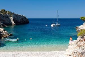 a boat in the water next to a beach at Buena Vis-ta Apartments with the Sea View in Vis