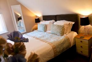 um quarto com uma cama com lençóis brancos e almofadas em The Sherwood em Skegness