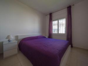 a bedroom with a purple bed and a window at InmoSantos Oasis D4 in Roses