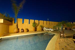 a swimming pool in a backyard at night at Riad Yacout in Meknès