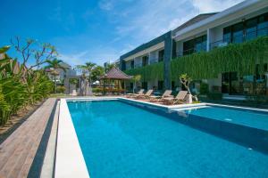 a swimming pool with chairs next to a building at Srikandi Inn in Jimbaran