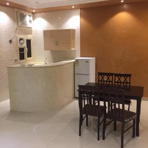 een keuken met een tafel en stoelen en een koelkast bij Beauty Rayan 2 in Jazan