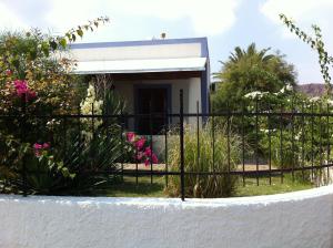 a fence in front of a house with pink flowers at Hotel Rojas in Vulcano