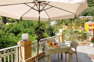 a table with an umbrella on a balcony at Rolandos Apartments in Agios Gordios