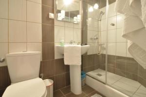 a bathroom with a toilet and a sink and a shower at Rolandos Apartments in Agios Gordios