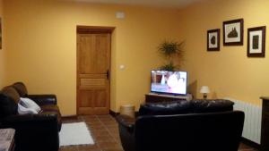 a living room with two leather couches and a television at El Condado Casa Rural in Fuentes de Oñoro