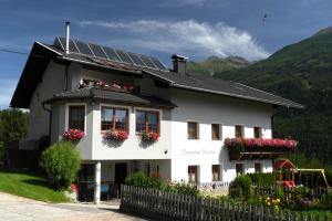 ein weißes Haus mit Blumen in den Fenstern in der Unterkunft Ferienhof Rindler in Schlaiten