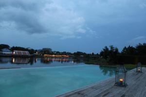 a swimming pool with a view of a river at night at The Glory River Kwai Hotel in Kanchanaburi