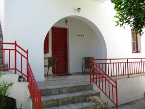 a cat sleeping in front of a building with a red door at Anna Studios in Katapola