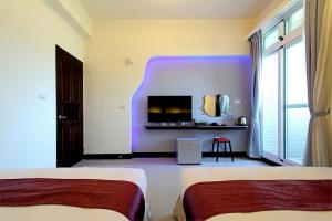 a hotel room with two beds and a tv at Blue Ocean Stars in Taitung City