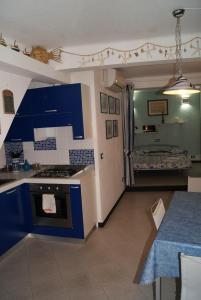 モンテロッソ・アル・マーレにあるChiara Cosy Studio Flat with ACのキッチン(青いキャビネット、コンロ、テーブル付)
