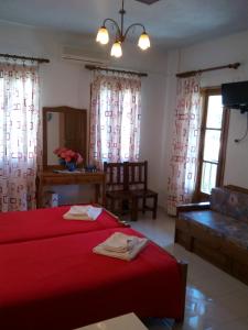 a bed room with a red bedspread and a large window at Sofia's Garden Studios in Skopelos Town