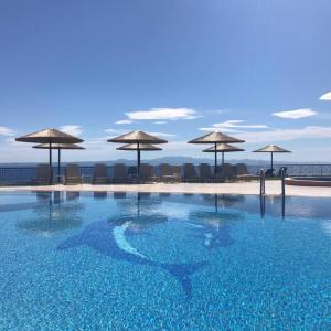 uma piscina com guarda-sóis numa praia em Aegean Blue Studios em Afitos