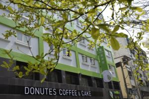 a building with a sign that reads donuts coffee and cake at Green Hotel - Fengjia in Taichung