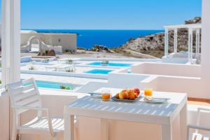 a table with a bowl of fruit and two glasses of orange juice at Katharos Pool Villas in Oia