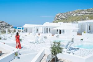 a woman standing in front of a white house at Katharos Pool Villas in Oia