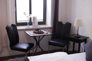 Zimmer mit 2 Stühlen, einem Tisch und einem Fenster in der Unterkunft Silentio Schletterstrasse in Leipzig