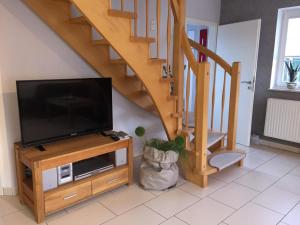 a living room with a flat screen tv and a staircase at Skippersin5 in Greetsiel