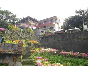 een stenen muur met een bloementuin bij KyuFun Komachi in Jiufen