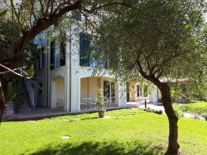 a white house with a tree in the yard at Albergo Blueline in Tellaro