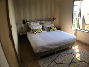 1 dormitorio con cama con almohadas y ventana en les jardins de la Matz, en Plouër-sur-Rance