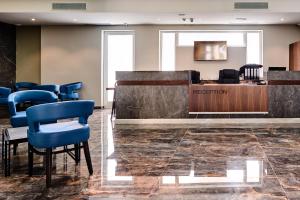 une salle d'attente avec une réception et des chaises bleues dans l'établissement The District Hotel, à San Ġiljan