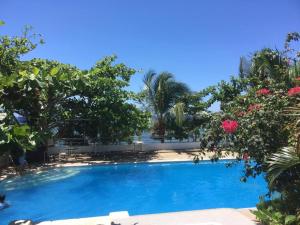 een groot blauw zwembad met bomen en roze bloemen bij Ucoy Beach Resort in Libertad