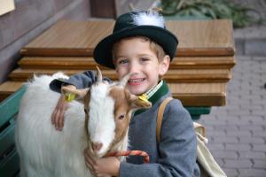 a young boy wearing a hat holding a goat at BIO-Bauernhof Hatzbauer in Maria Alm am Steinernen Meer