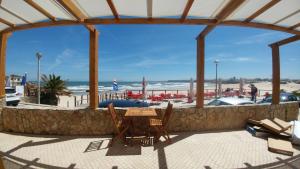 a patio with a table and chairs and the beach at The Wave Baleal in Baleal