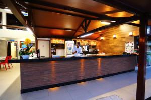 a man standing at a bar in a restaurant at Coroa Vermelha Beach - All Inclusive in Porto Seguro