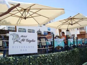 two people sitting in chairs under umbrellas at a restaurant at Hotel Giglio in Lampedusa
