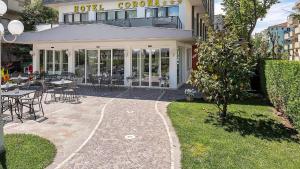 a building with a patio and tables and chairs at Hotel Corona in Riccione
