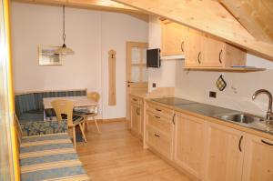 eine Küche mit Holzschränken, einem Tisch und einem Esszimmer in der Unterkunft Residence Ciasa Dl Mone in Kolfuschg