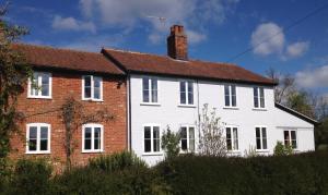 uma grande casa branca com um tijolo vermelho em Snipe Vineyard Cottage em Woodbridge