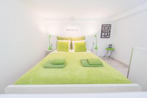 a white bedroom with a large bed with green blankets at happy home FOX - apartment with free Pinball Machine in Budapest