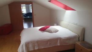 Stadtschenke في فيلاخ: غرفة نوم بسرير ابيض ومخدة حمراء