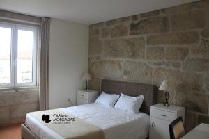 a hotel room with a bed and a stone wall at Casa Das Morgadas in Nelas