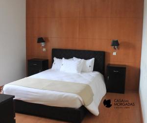 een slaapkamer met een groot bed met witte lakens en kussens bij Casa Das Morgadas in Nelas