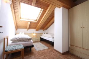 1 dormitorio en el ático con 2 camas y ventana en Agritur Chelodi, en Cavalese