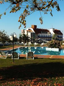 una piscina con sillas y edificios en el fondo en Hotel Luz de Luna, en Portonovo