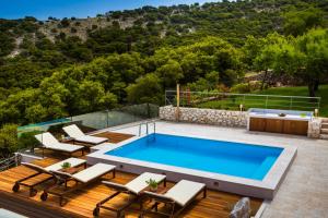 una piscina en una terraza con sillas y una piscina en Iconic Villas - Villa Rosa, en Agia Efimia